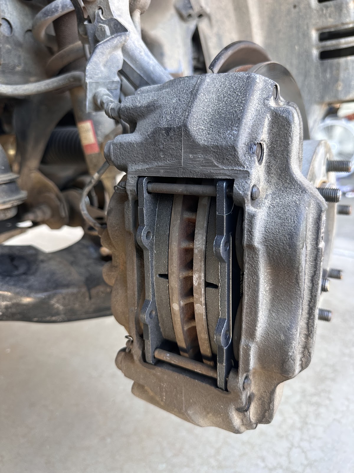 Brake caliper and rotor exposed with the wheel off during a brake job